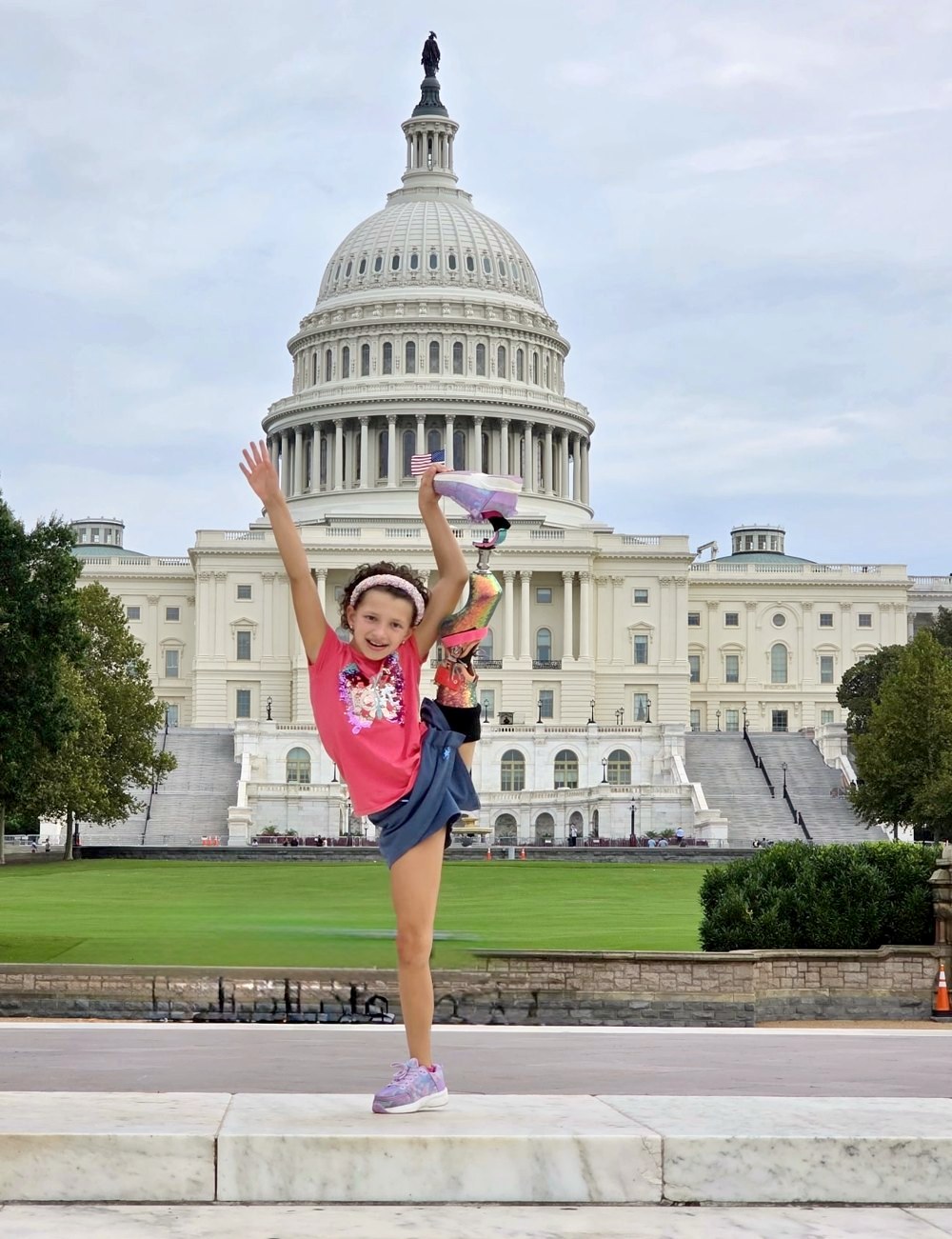 Belle doing a high kick with her prosthetic leg in front of the U.S. Capitol