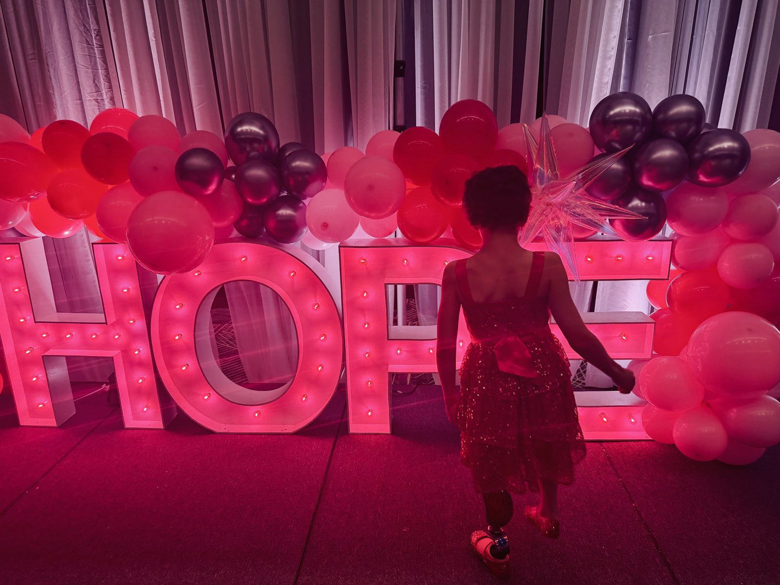 Belle walking toward a lit-up HOPE sign