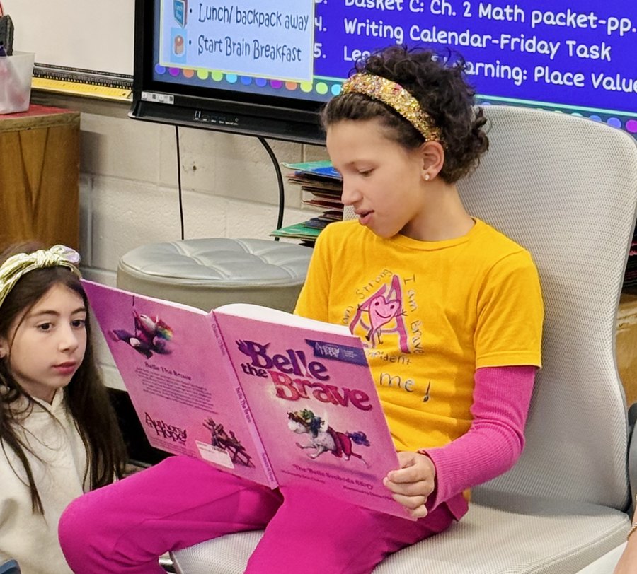 Belle reading her book Belle The Brave aloud to a classroom